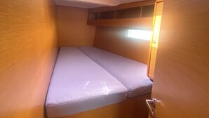 Quarto compacto com beliche, uma pequena janela e luminária no teto.