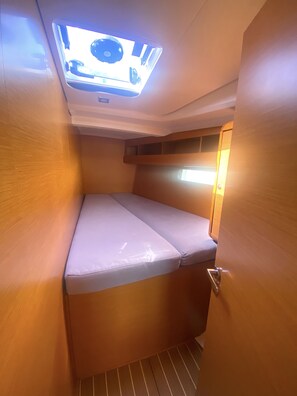Ein kleines Zimmer mit Etagenbett, kleinem Fenster und Deckenleuchte.
