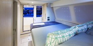 A bedroom with a bed, a window with blinds, a door leading outside, and a small table.