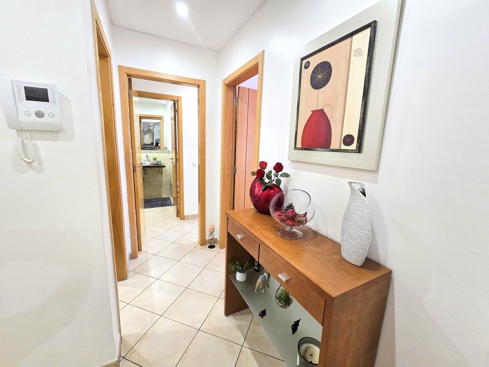 A hallway with a wooden console table, a telephone, and a framed artwork on the wall.