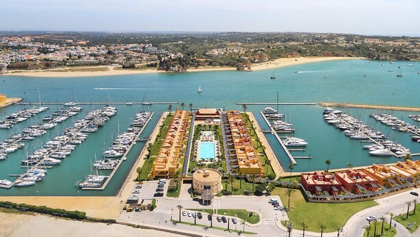 Uma marina com vários barcos atracados, uma piscina e um hotel com um edifício circular.