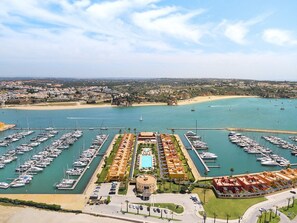 Ein Yachthafen mit zahlreichen Booten, einem Schwimmbad und einem Hotel mit kreisförmigem Gebäude.