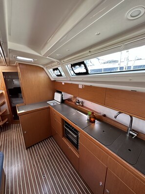 A compact galley with a sink, stove, and storage cabinets.