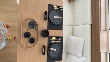 A compact living area with a dining table set for two, a sofa, and a small window.