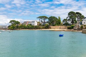 Une ville côtière avec des maisons, une plage de sable et une eau calme.