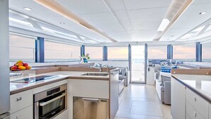 A modern kitchen with a view of the sea, a dining area with a view, and a control station. - Sun-Kissed Sailing Adventure in Islas Sarónicas (Piraeus)