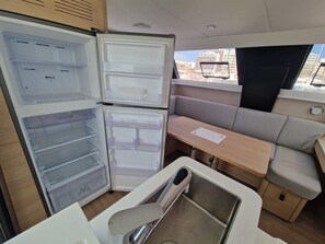A compact kitchenette with a refrigerator, sink, and bench seating.