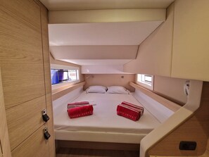 A compact cabin with a single bed, a small window, and a built-in storage cabinet.