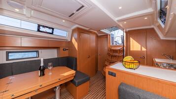 A compact galley with a dining table, a seating area, a small kitchen, and a window.