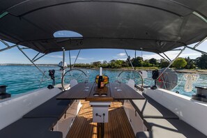 A boat deck with a table, two wine glasses, a bottle of champagne, and a fruit basket. - Sun-Kissed Sailing Adventure in Zadar, Croatia (Zadar)