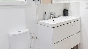 Une salle de bain blanche avec des toilettes, un lavabo et un miroir.