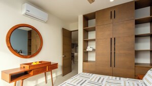 A bedroom with a bed, a wooden wardrobe, a mirror, and a built-in air conditioning unit. - Rooftop Penthouse in Akumal jungle — steps to the beach (AKUMAL)