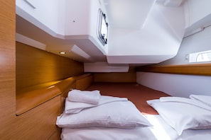 Una cabana amb un llit, almoinos, una finestra i un panell de fusta al capçal.