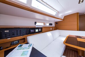 A boat interior with a control panel, a white cushioned seating area, and a table. - Sun-Kissed Sailing Adventure in the Ionian Islands, Lefkada (Lefkada)