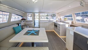 Interior moderno de embarcación con comedor, cocina y zona de estar.