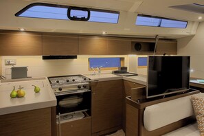 Cocina pequeña con estufa, horno, fregadero y televisor de pantalla plana.