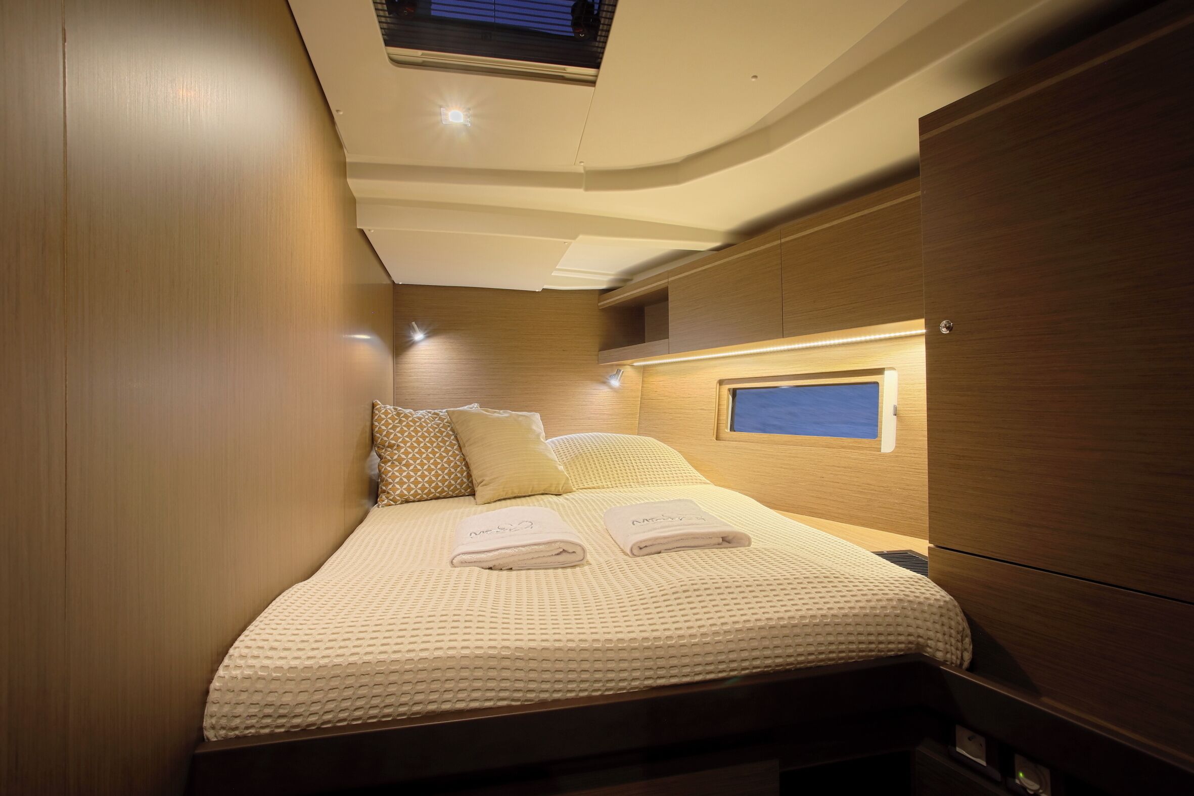 A compact, well-lit bedroom with a bed, pillows, and a small window.