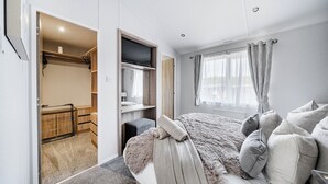 Un dormitorio con cama, televisor, armario y baño.