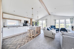 Una cocina moderna con armarios blancos, una isla central y taburetes de bar.