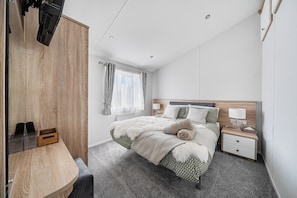 Een slaapkamer met een bed, nachtkastje, lamp en een kledingkast.