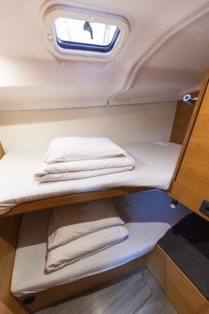 A bunk bed with a skylight, a wooden cabinet, and a small window.