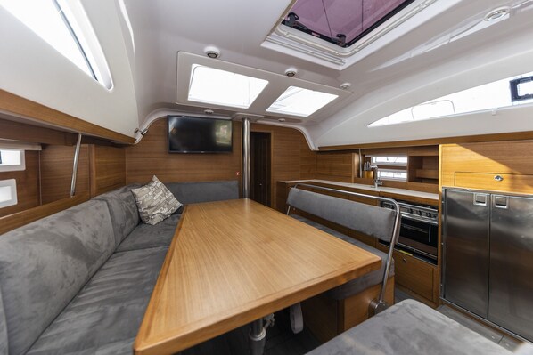 A compact galley with a wooden table, a built-in oven, and a refrigerator.
