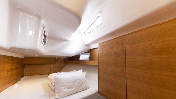 Une cabine compacte comprenant un lit simple, un petit coin salon et un téléviseur intégré.