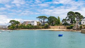 Une ville côtière avec des maisons, une plage de sable et une eau calme.