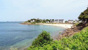Un hôtel situé sur la côte, composé de plusieurs bâtiments, avec une plage de sable fin et une eau d’un bleu cristallin.