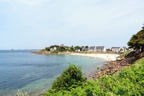 Un hôtel situé sur la côte, composé de plusieurs bâtiments, avec une plage de sable fin et une eau cristalline.