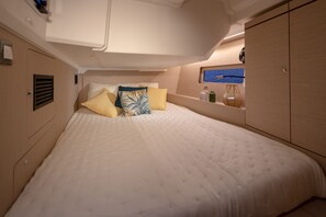 Ein Schlafzimmer mit einem Bett, Kissen, einem Regal mit Gegenständen und Meerblick.