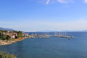 Un port de plaisance situé sur la côte, où sont amarrés de nombreux voiliers, avec un phare et des immeubles résidentiels le long de la rive.