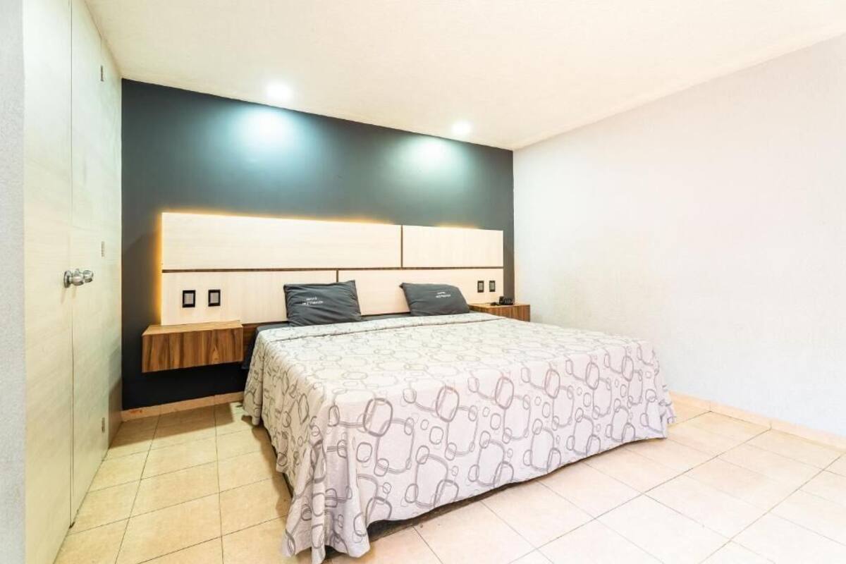 Una camera da letto con un letto, comodini, una lampada a parete e una porta.