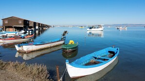 Un paysage paisible au bord de l’eau, avec plusieurs bateaux amarrés, un bâtiment en bois et un ciel bleu dégagé.
