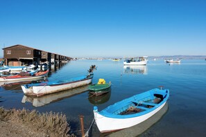 Un paysage paisible au bord de l’eau, avec plusieurs bateaux amarrés, un bâtiment en bois et un ciel bleu dégagé.