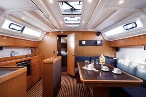 A compact galley with a dining area, wooden cabinetry, and a small seating space. - Sun-Kissed Sailing Adventure in the Dodecanese Islands (Kos)