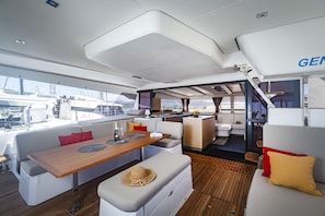 Schauplatz in einem Yachten-Interieur mit Essbereich, Sitzgelegenheiten und Blick auf den Yachthafen.