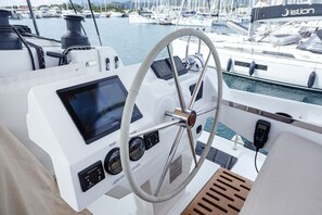 A boat's helm station with a steering wheel, control panel, and a view of the marina. - Sun-Kissed Sailing Adventure in the Ionian Islands, Lefkada (Lefkada)