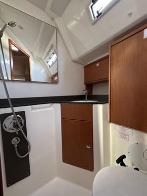 A compact bathroom with a shower, a mirror, and a sink. - Sun-Kissed Sailing Adventure in Zadar, Croatia (Drage)