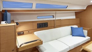 A compact cabin with a white sofa, a small table, and a control panel. - Sun-Kissed Sailing Adventure in the Ionian Islands, Lefkada (Lefkada)