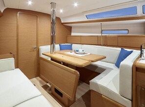 A compact boat interior with a wooden bench, a small table, and a cushioned seating area. - Sun-Kissed Sailing Adventure in the Ionian Islands, Lefkada (Lefkada)