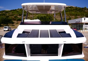 Ein Boot mit überdachter Deckfläche, Solarmodulen und einer Kabine mit Fenstern.