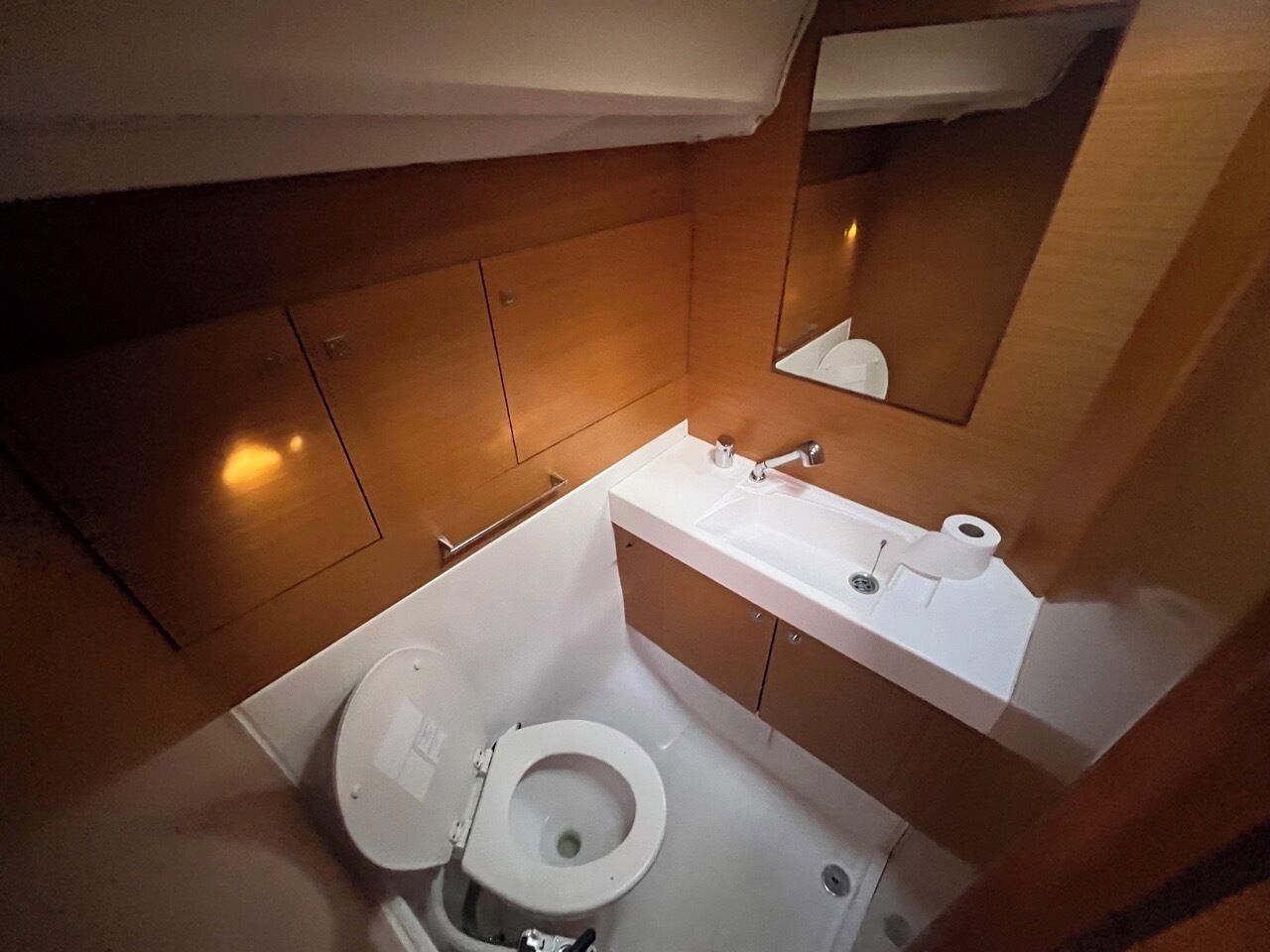 Une petite salle de bain comprenant des toilettes, un lavabo et des placards de rangement.