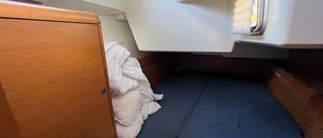 Uma cabana pequena com uma cama beliche, um armário de madeira e uma janela com persianas.