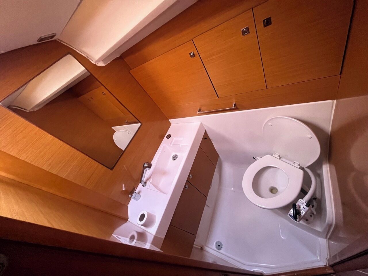 A compact bathroom with a toilet, sink, and shower.