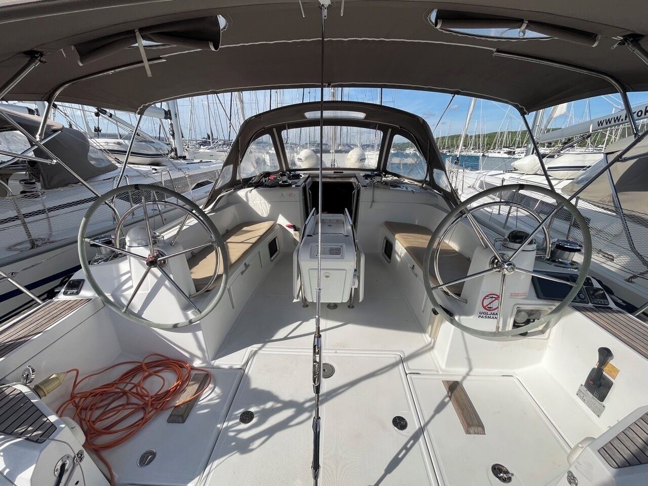 A boat's deck with two steering wheels, a central console, and a network of ropes.