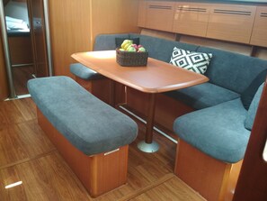 A compact kitchenette with a small table, bench seating, and a basket of fruit.