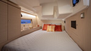 Quarto com cama, almofadas, espelho e janela com vista.