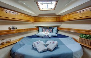 A compact boat cabin with a bed, wooden cabinetry, a skylight, and a small plant. - Sun-Kissed Sailing Adventure in the Ionian Islands, Lefkada (Lefkada)
