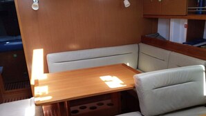 A compact interior with a wooden table, cushioned seating, and a built-in shelf.